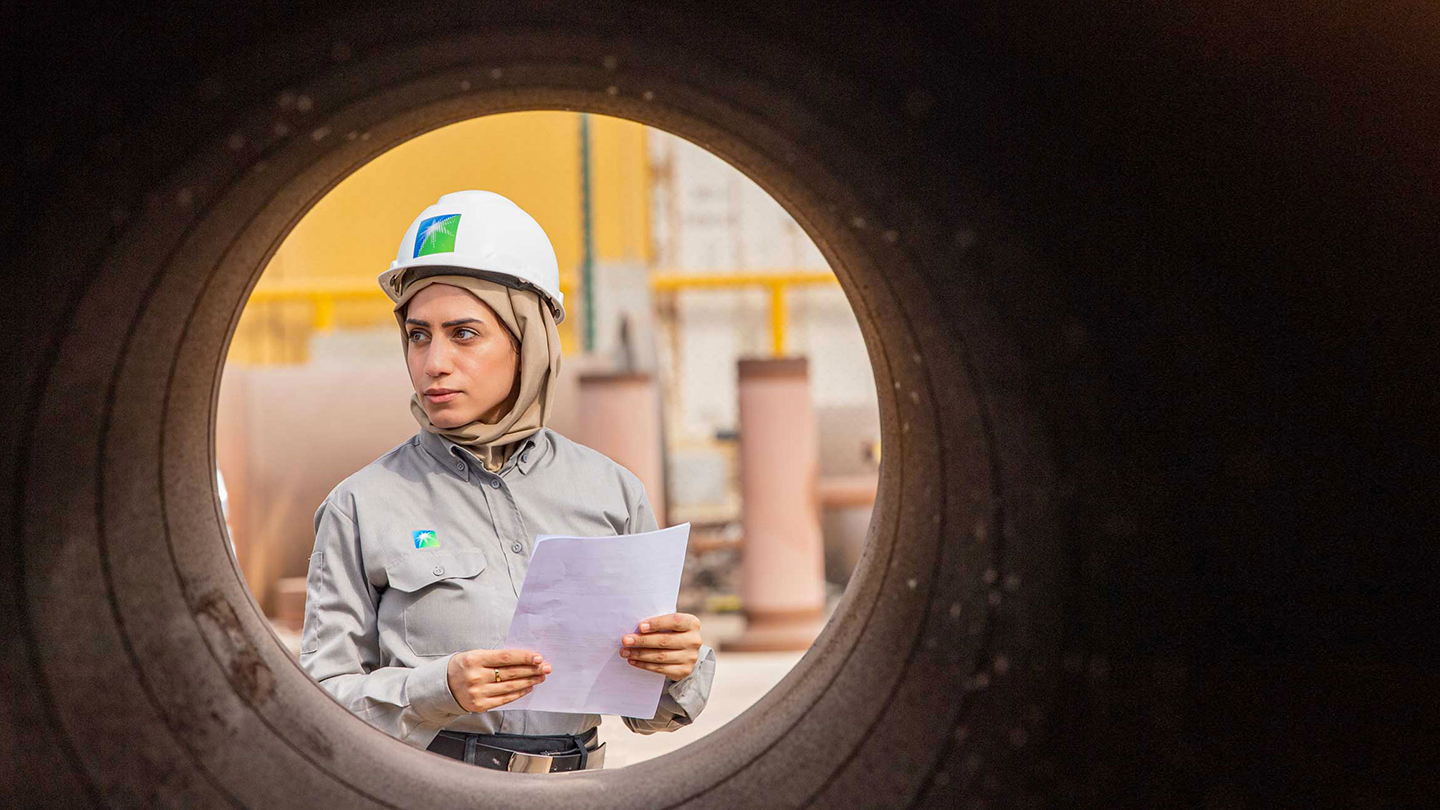 إحدى موظفات أرامكو السعودية تنظر من خلال خطوط الأنابيب