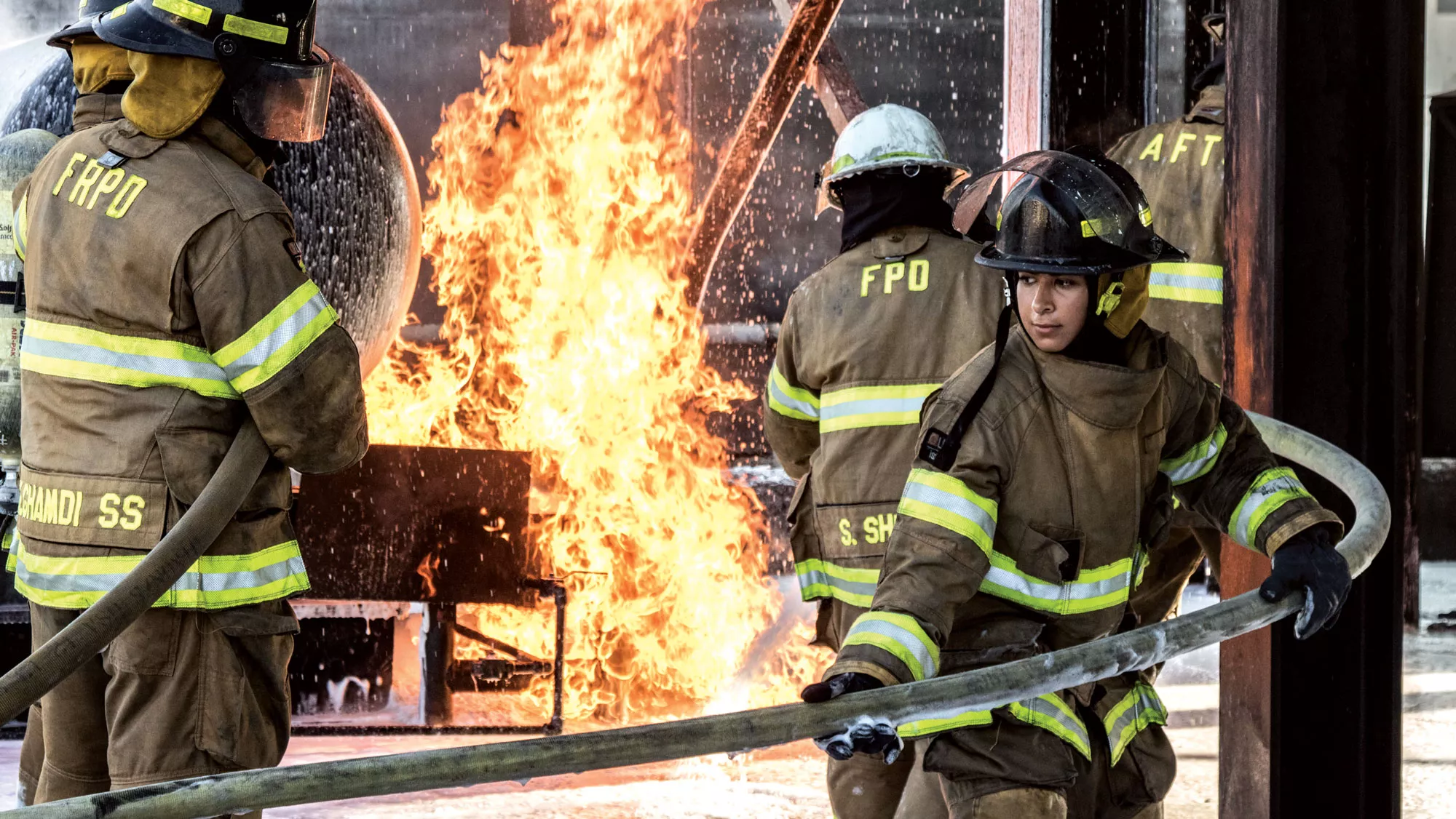 Female firefighter in protective clothing with a fire in the background