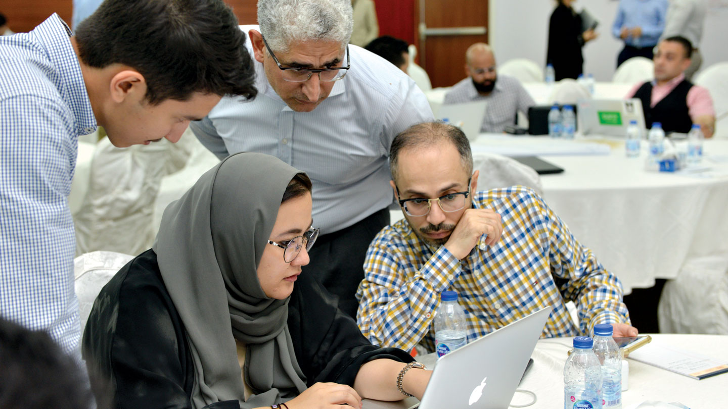 Team at a workshop gather around a laptop