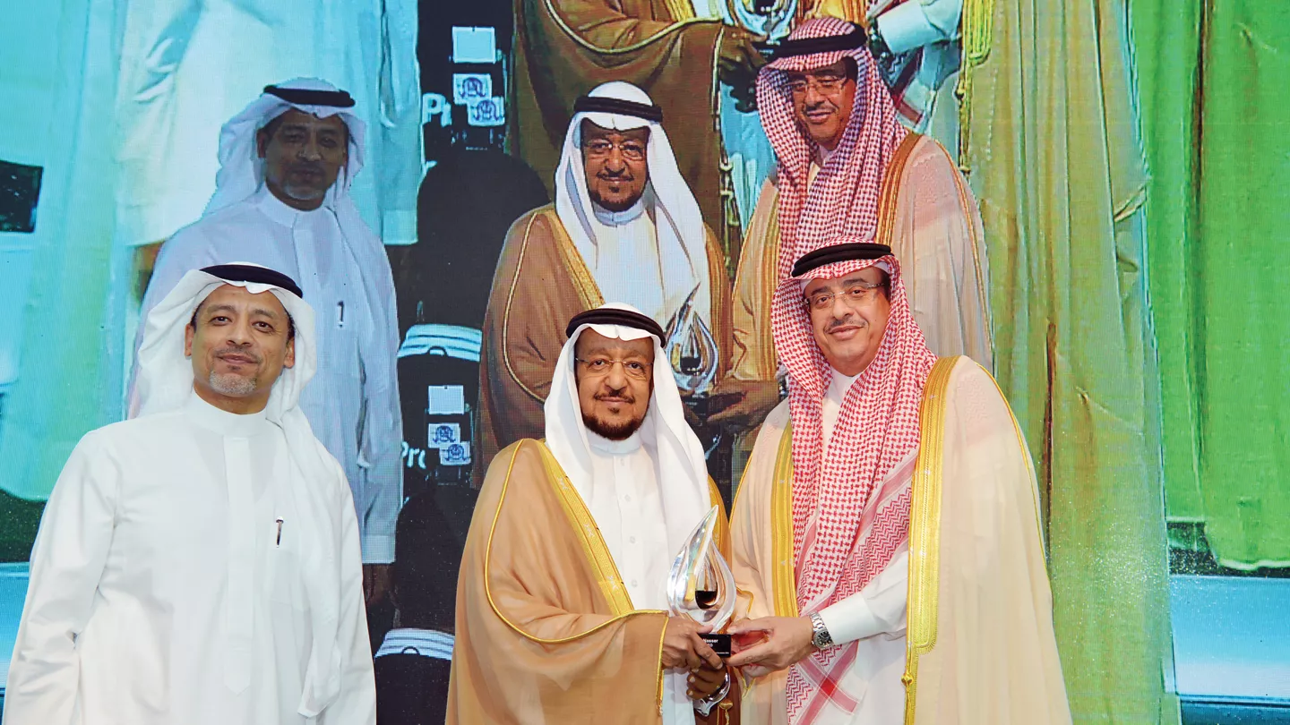 نبيل الجامع يتسلَّم درع تكريم أرامكو السعودية خلال حفل تخريج الدفعة التاسعة لطلاب المعهد السعودي التقني للبترول، ويبدو في منتصف الصورة عبدالرحمن بن محمد عبدالكريم، وإلى اليسار بسام البخاري.