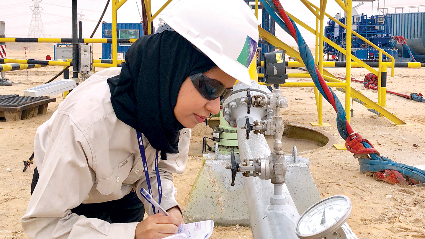 Petroleum engineer inspecting a valve on Aramco oil production site